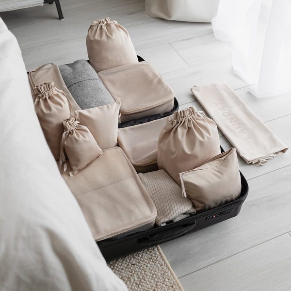 Packing organizer set for suitcase in beige in a bedroom, designed in Stockholm