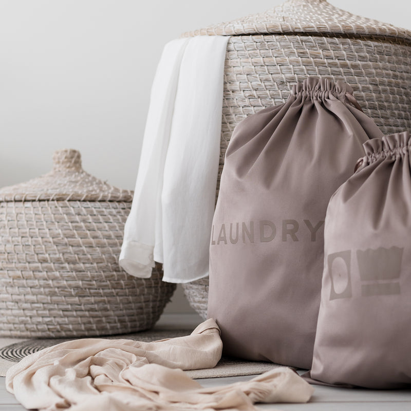 Two laundry bags in the color brown in front of two beige baskets