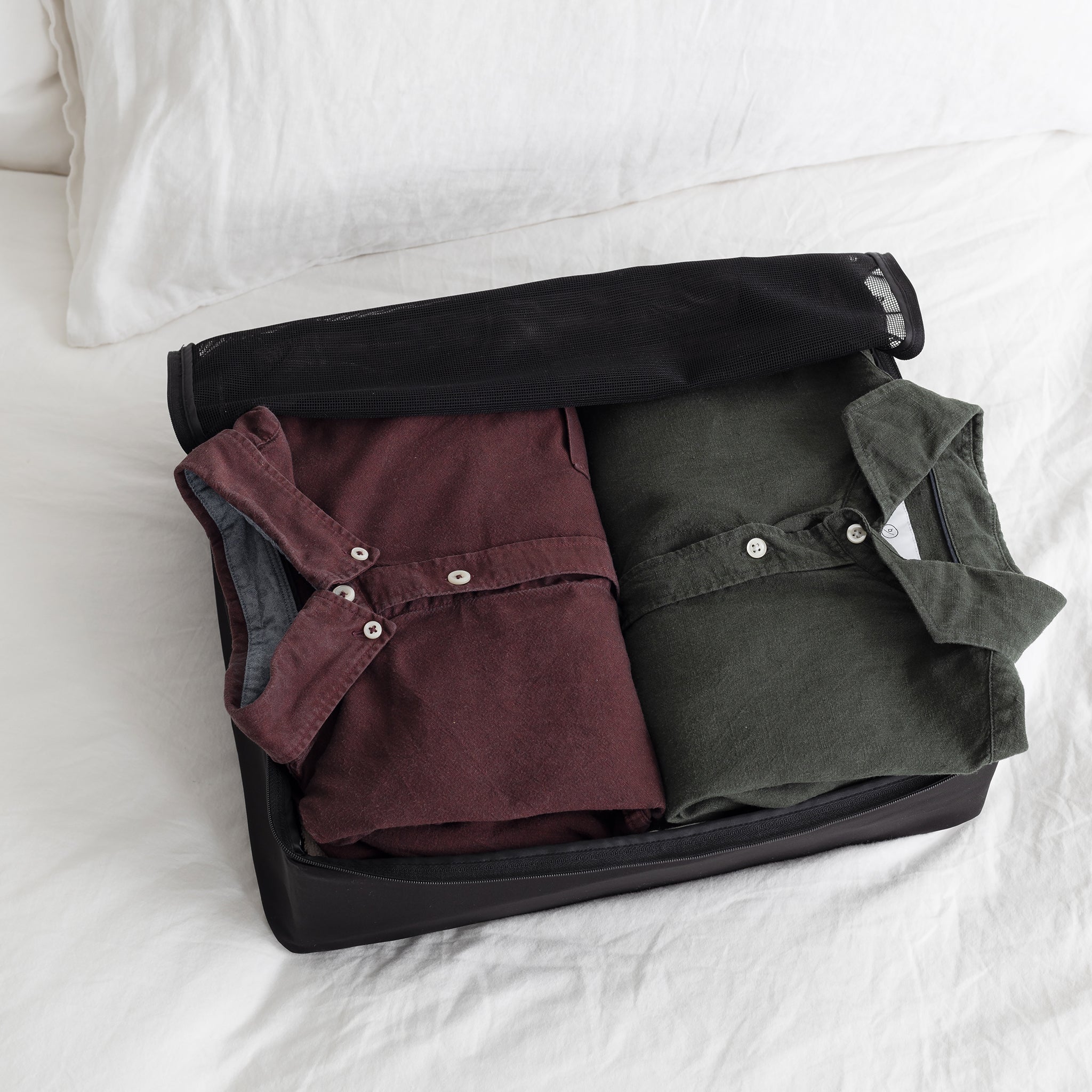 Folded button shirts packed flat inside an open travel packing cube