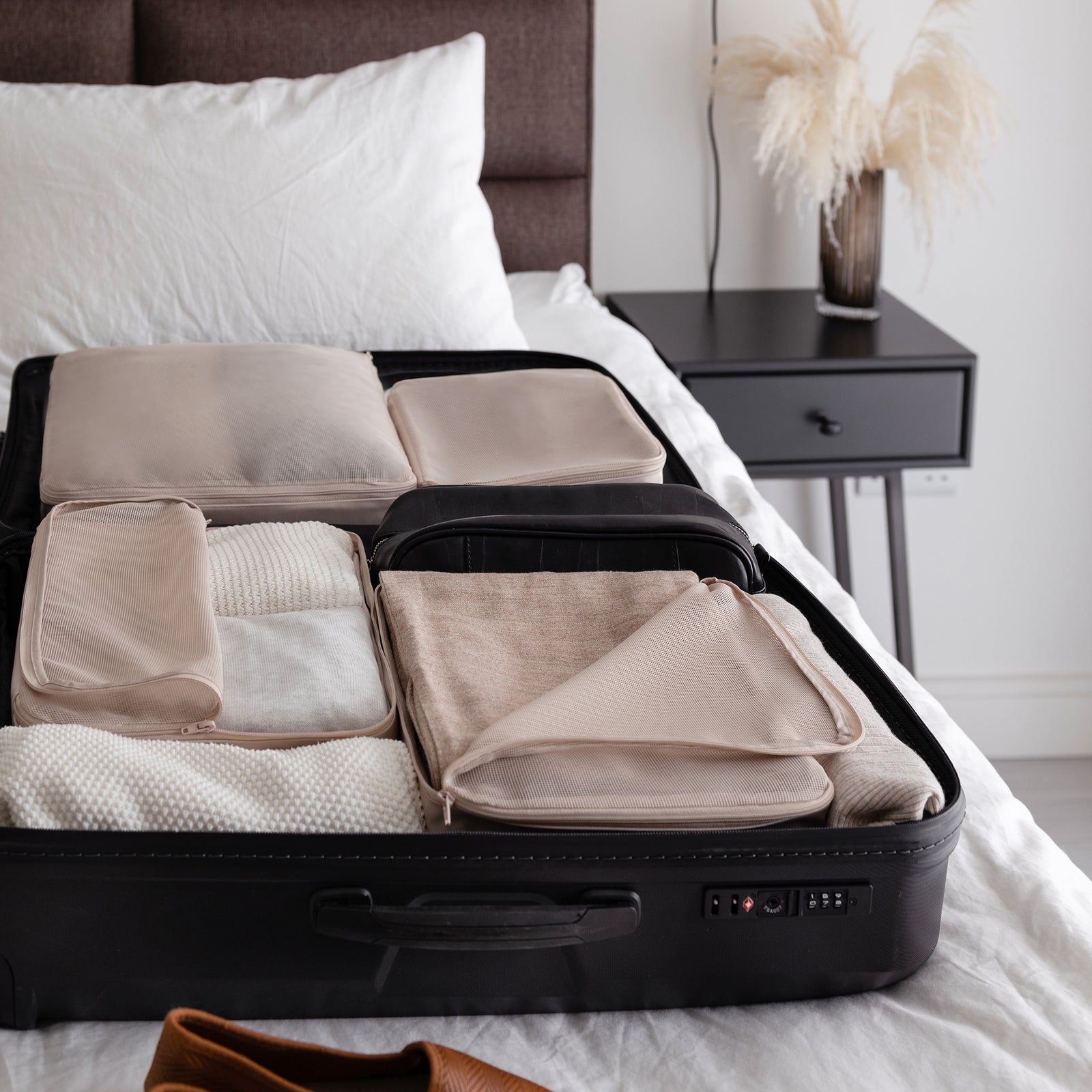 Neutral packing organizers arranged neatly inside open travel luggage