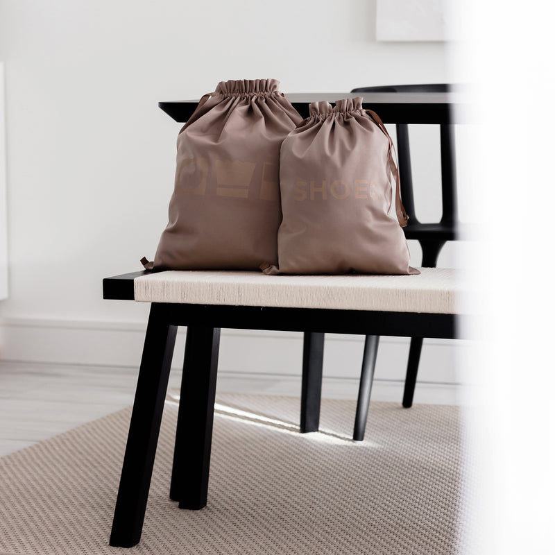 Large laundry bag and a shoe bag in the color brown on top of a bench